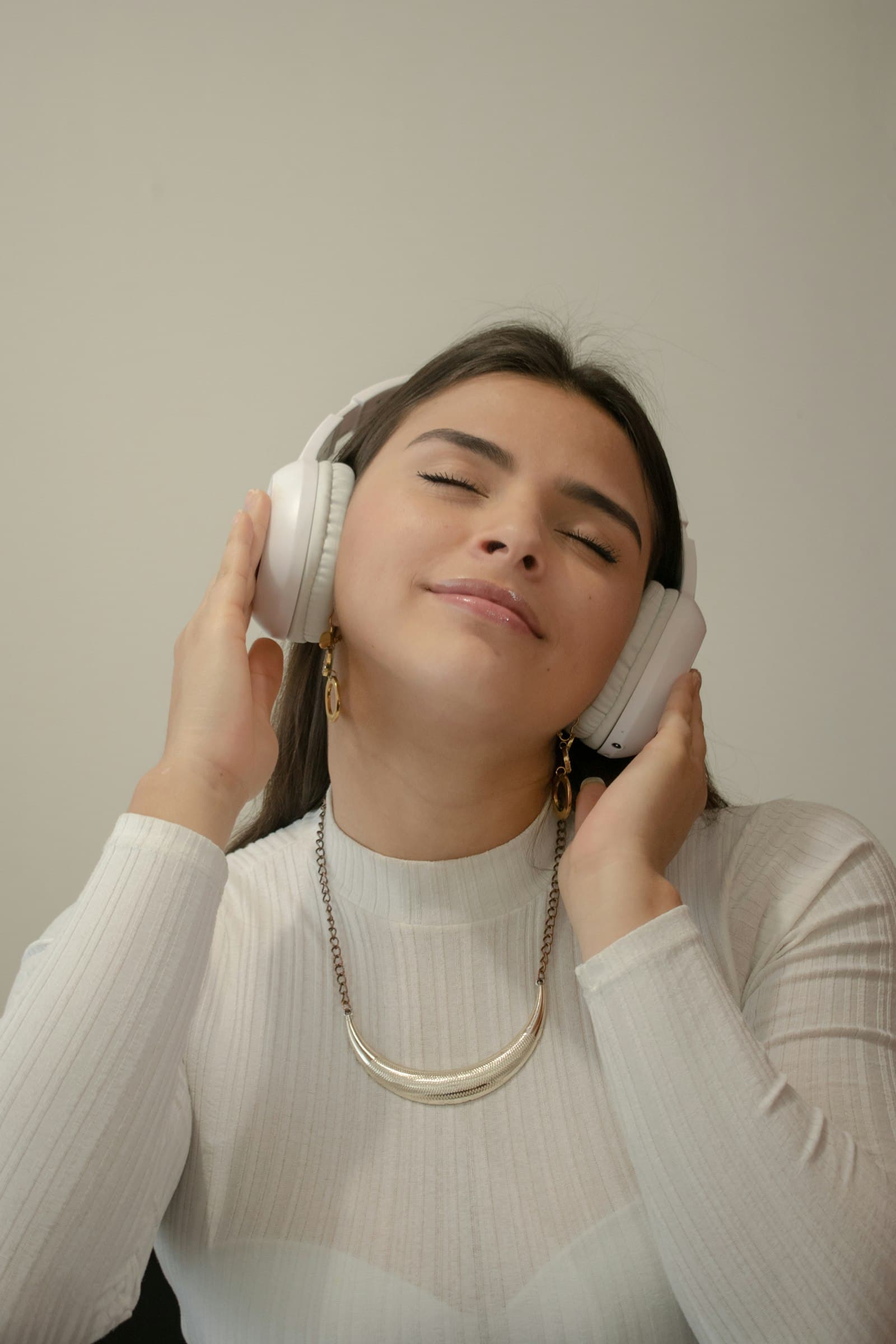 A person listening through headphones with their eyes closed