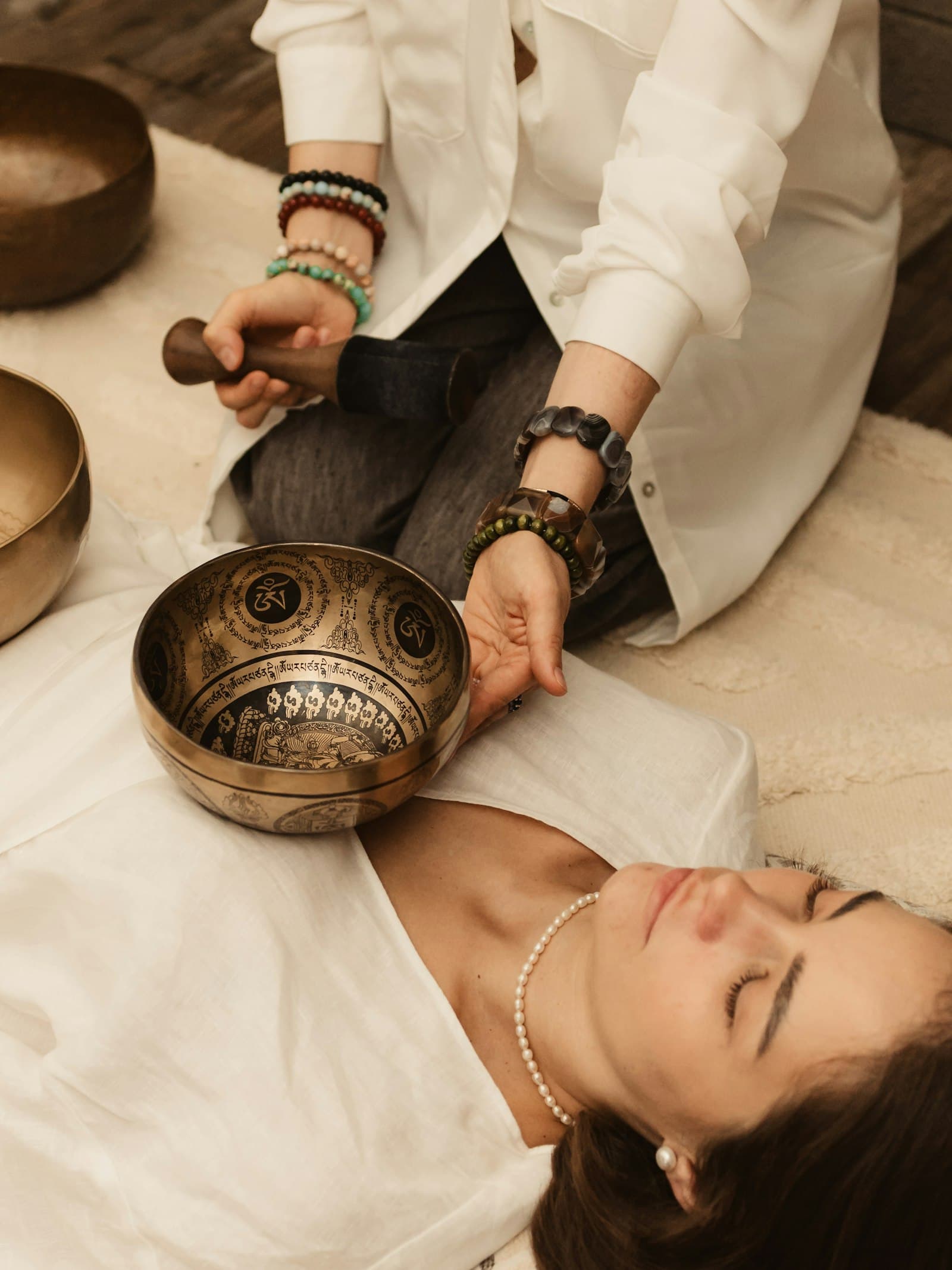 A practitioner playing singing bowls over a person lying down