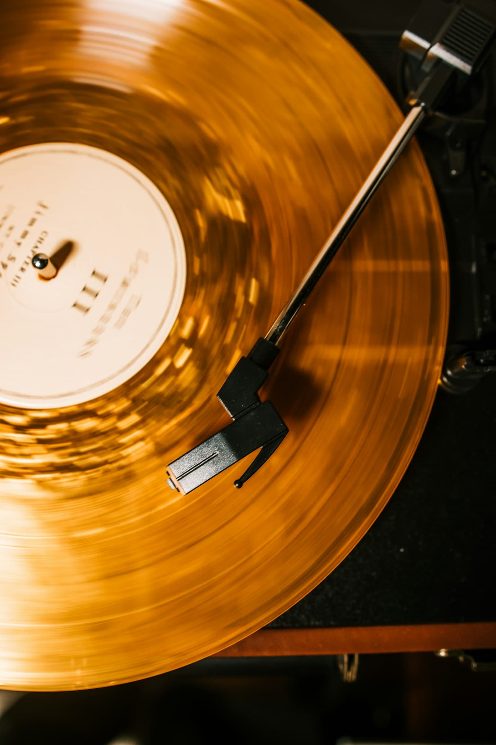 An amber vinyl record spinning on a turntable in warm light