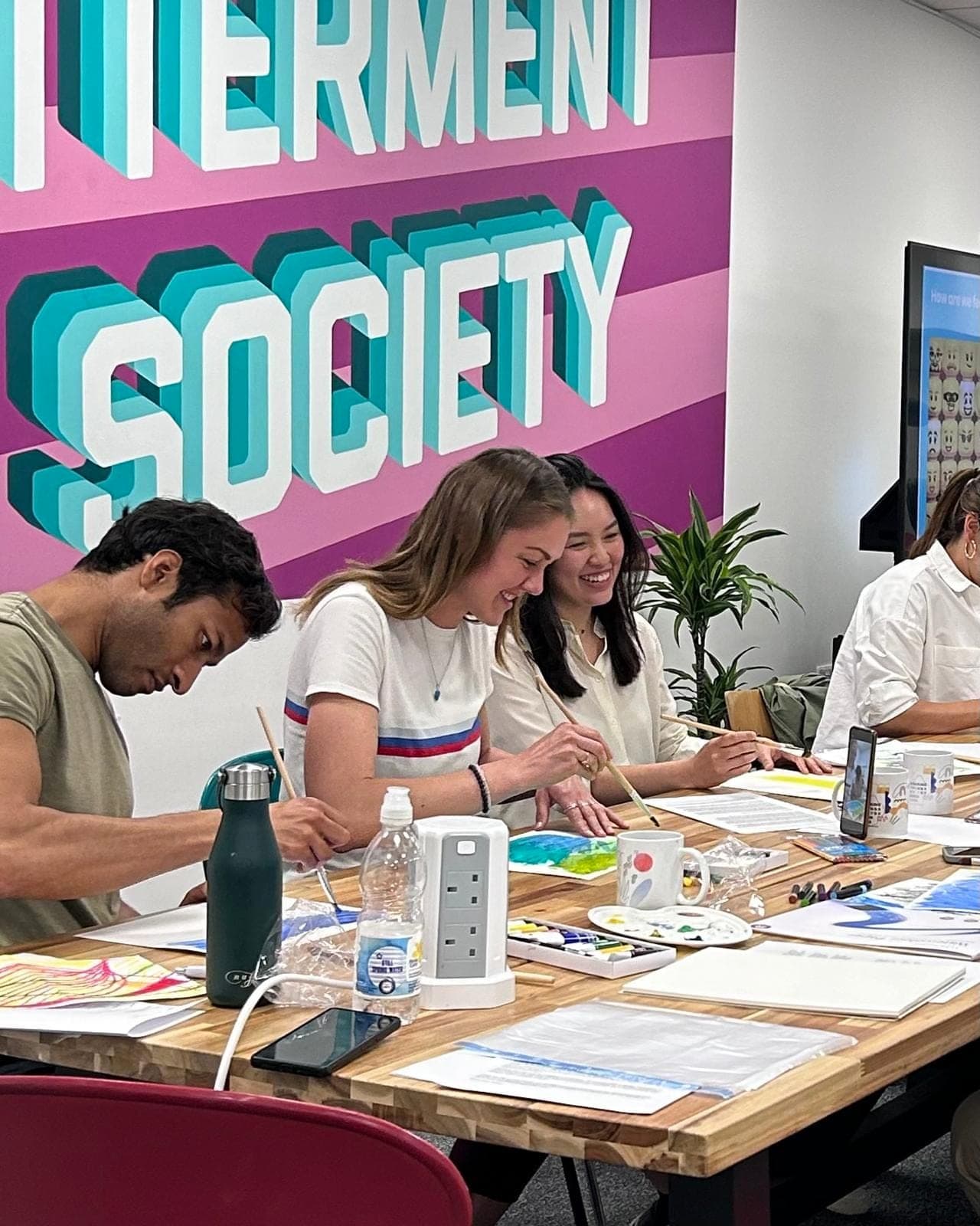 Participants painting together and laughing during a MindHug art session