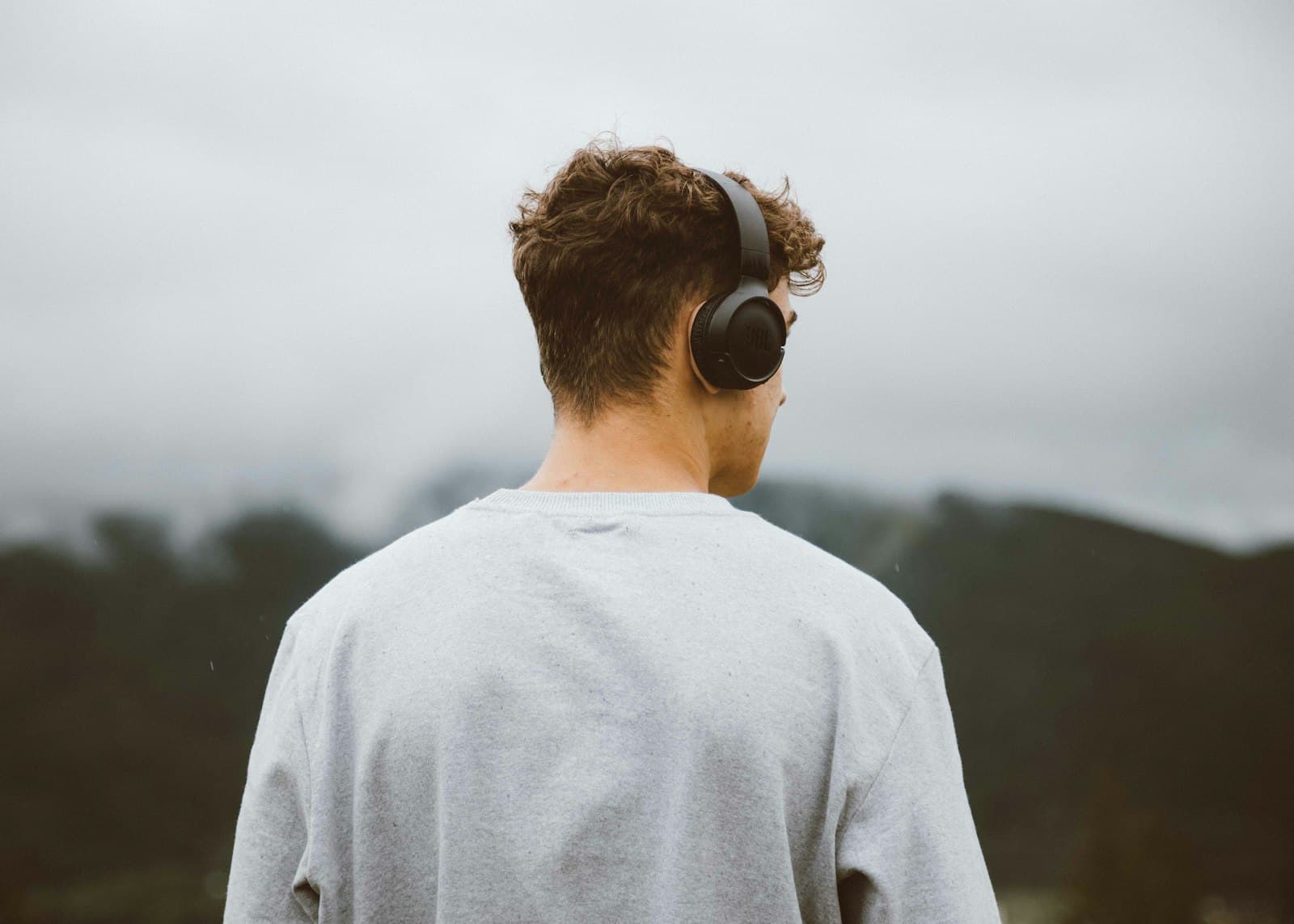 A person wearing headphones outdoors looking at the hills