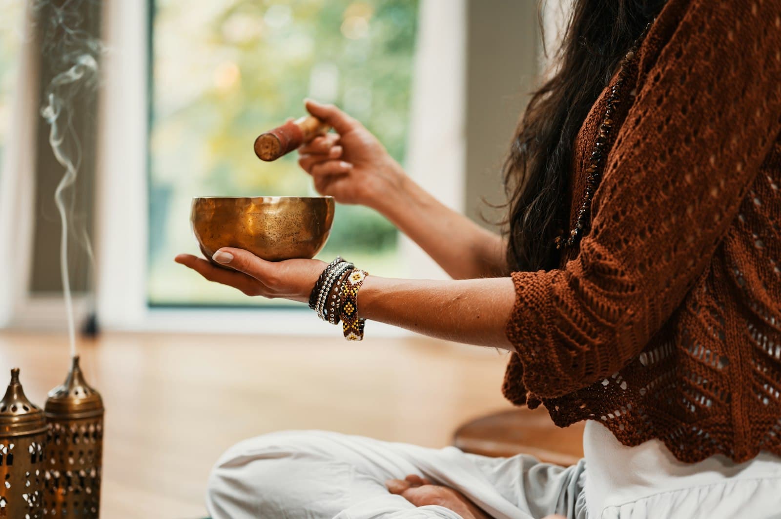A singing bowl and striker beside burning incense